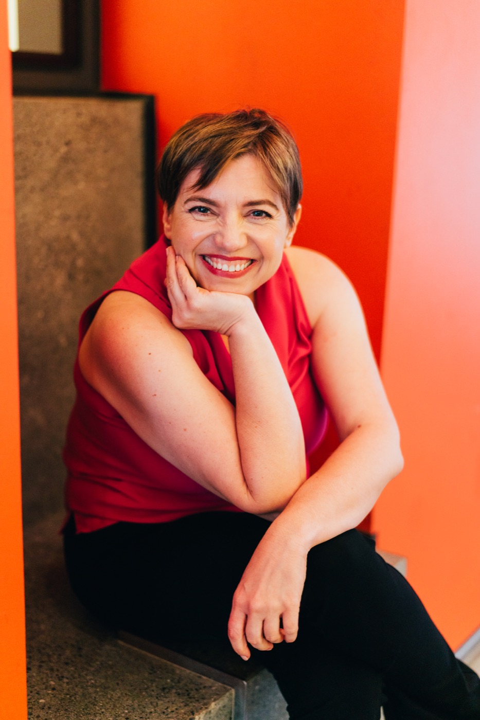 Ana smiling, seated with her chin resting on her hand.